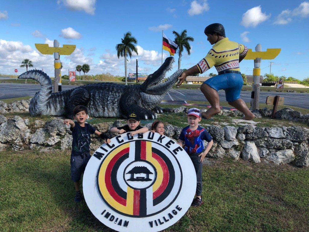 Image: Children pose for a photo at the main entrance to the Miccosukee Indian Village