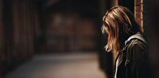 The Redemptive Work of Unmerited Suffering: What I’m Learning Image: A woman stands with her back to a wall, looking down at the ground