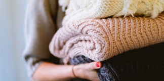 Image: A woman holds of stack of knitted sweaters