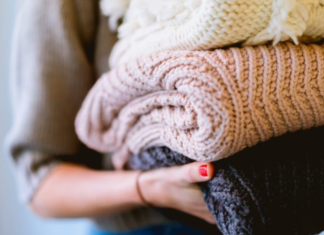 Image: A woman holds of stack of knitted sweaters