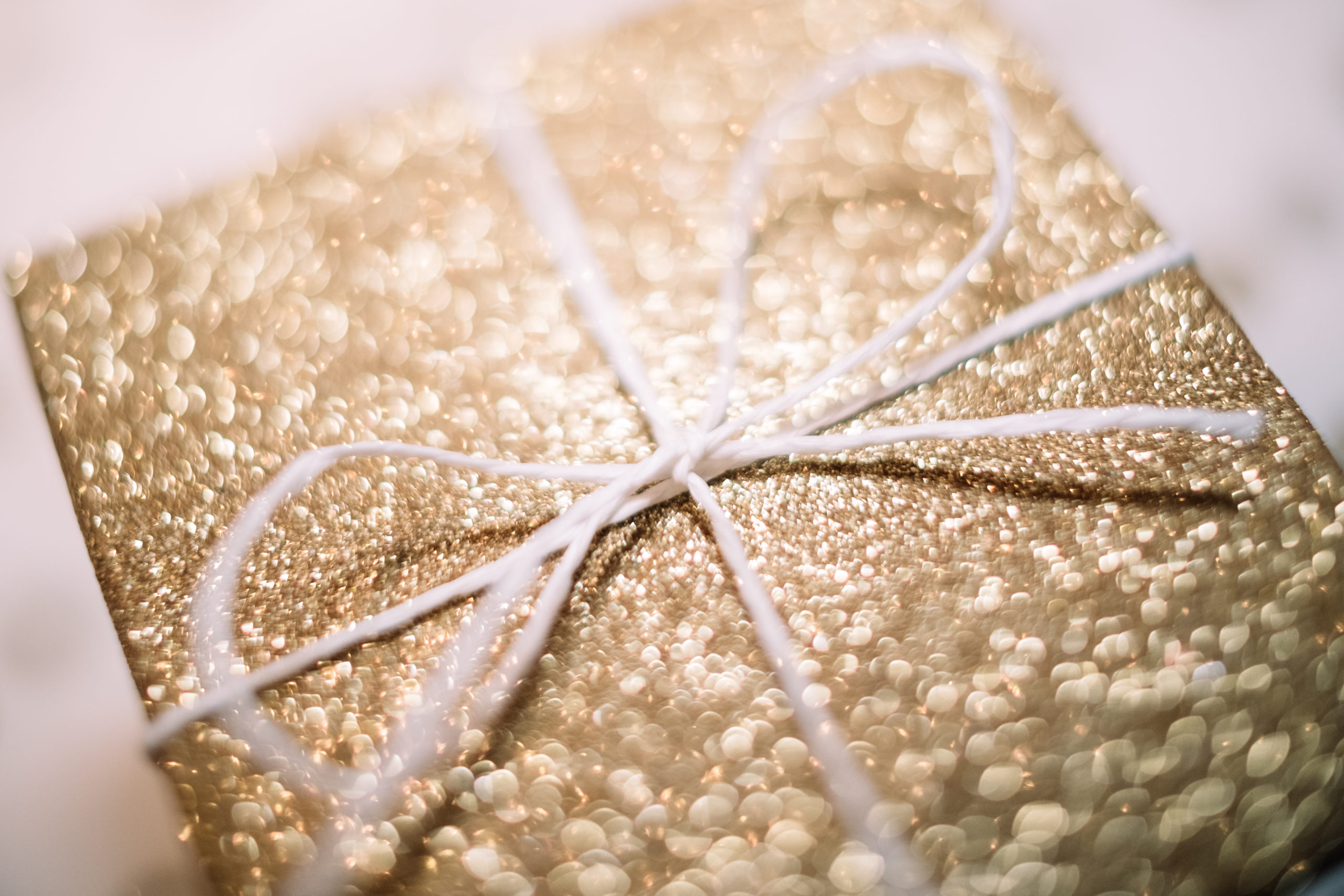Image: A rectangular gift box wrapped in gold paper and tied with white string