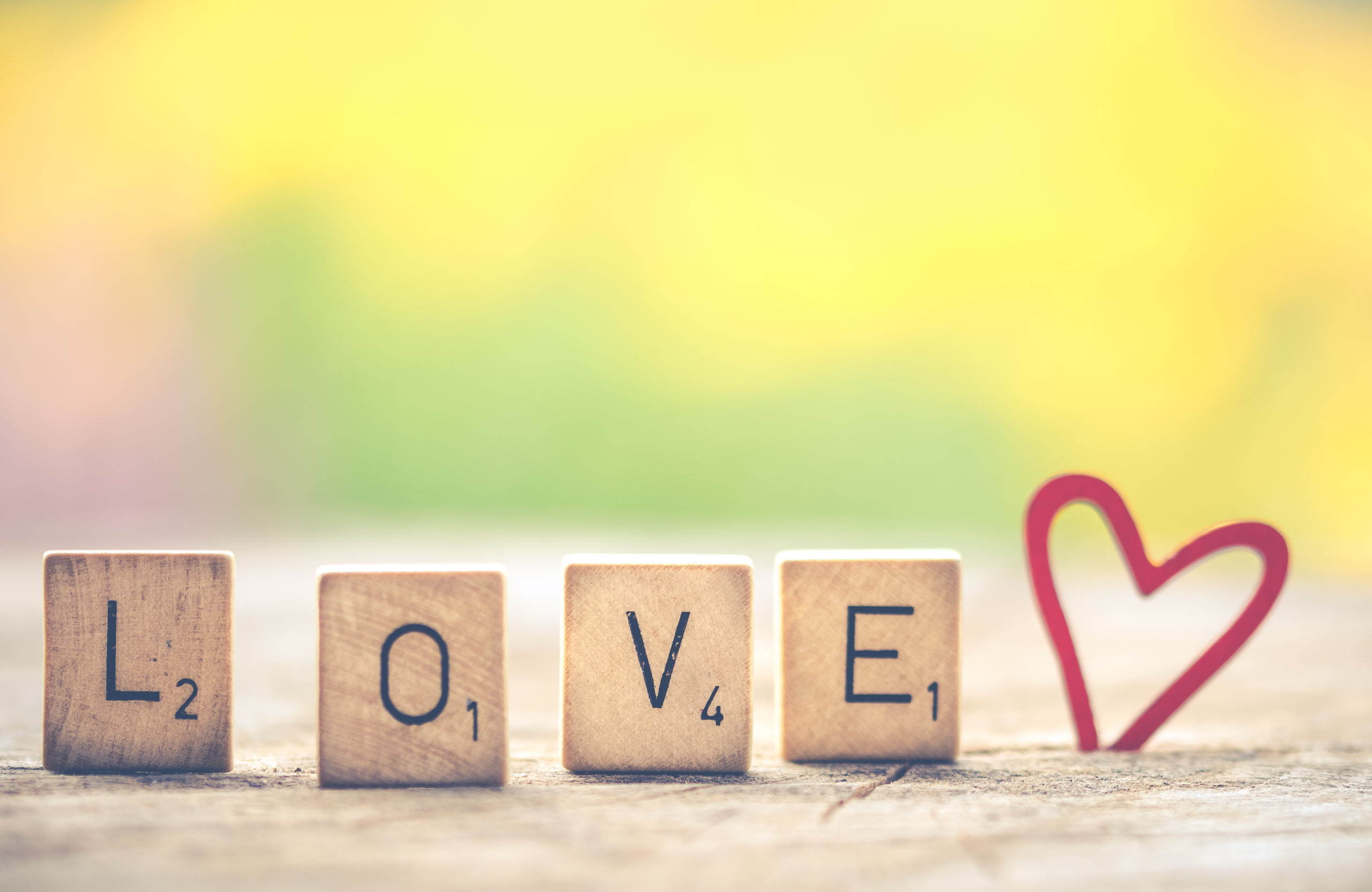 Image: Scrabble letters spelling out LOVE against a background of bright spring colors
