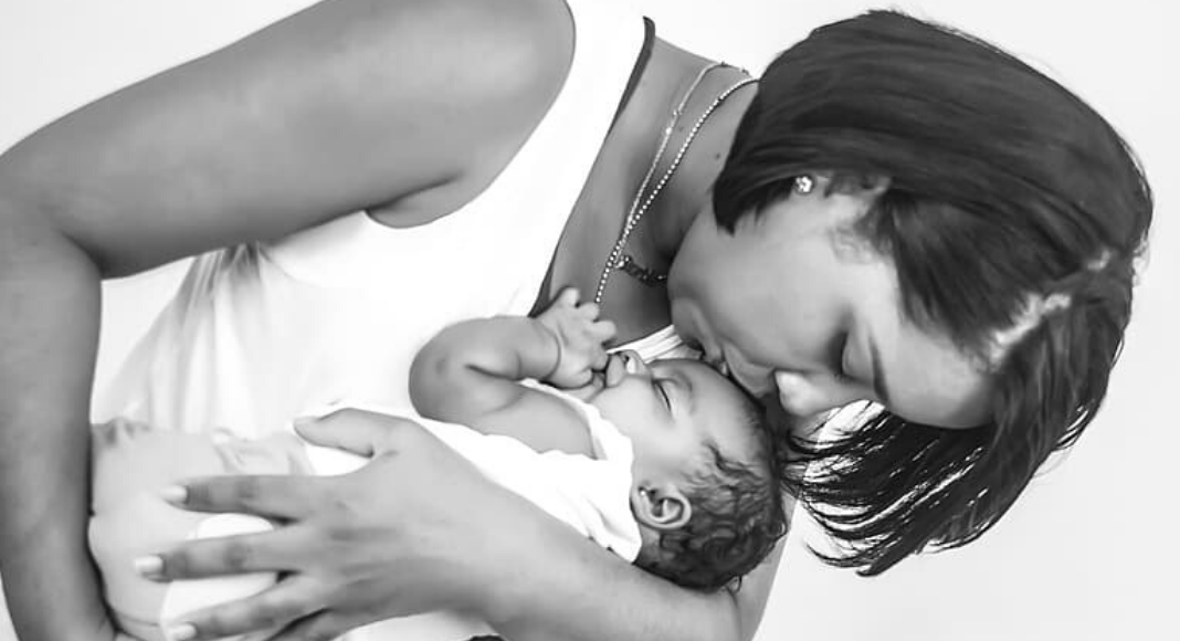Image: A mother holds and kisses her sleeping infant