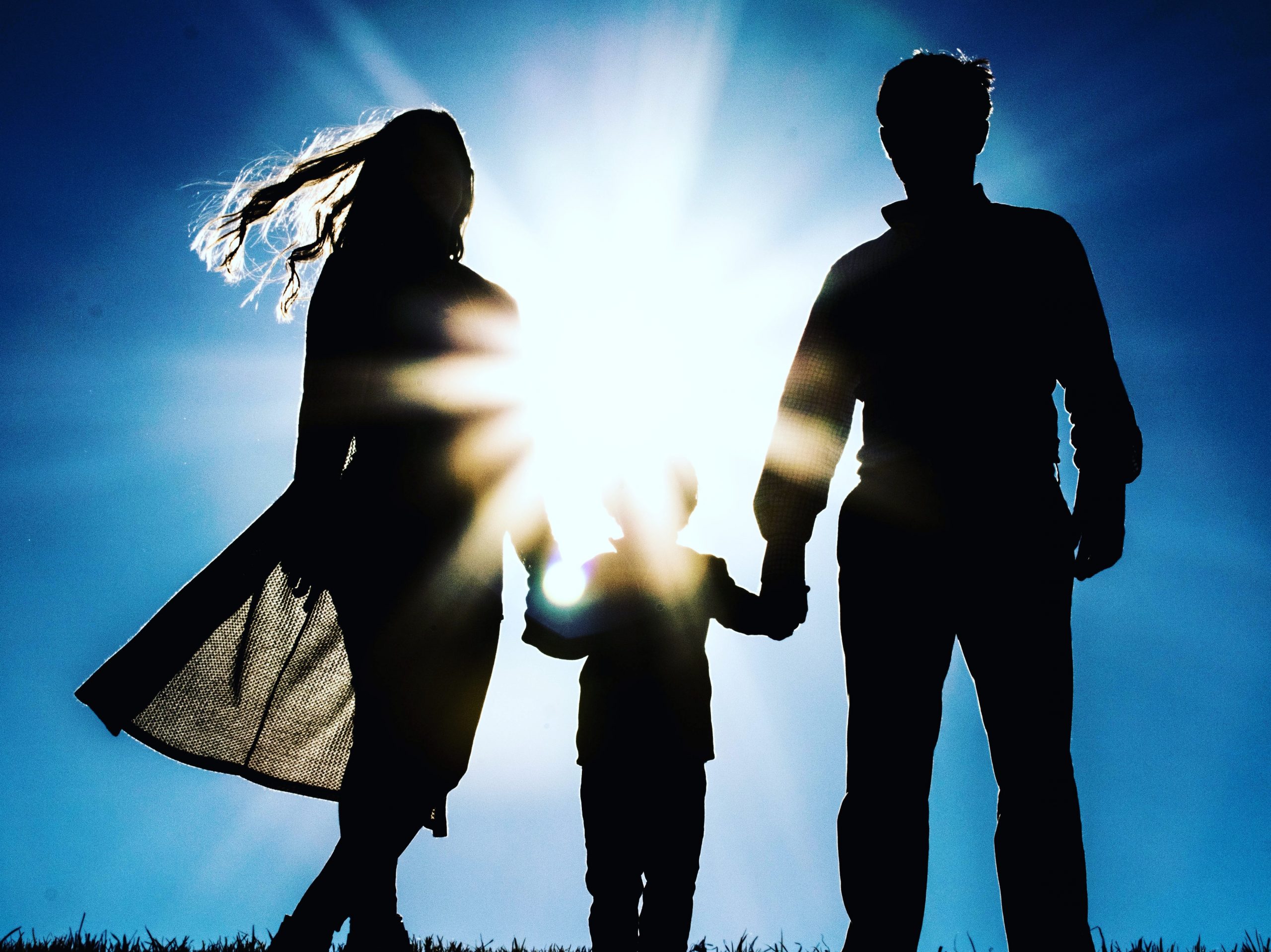 Image: A silhouette of a family against a blue sky