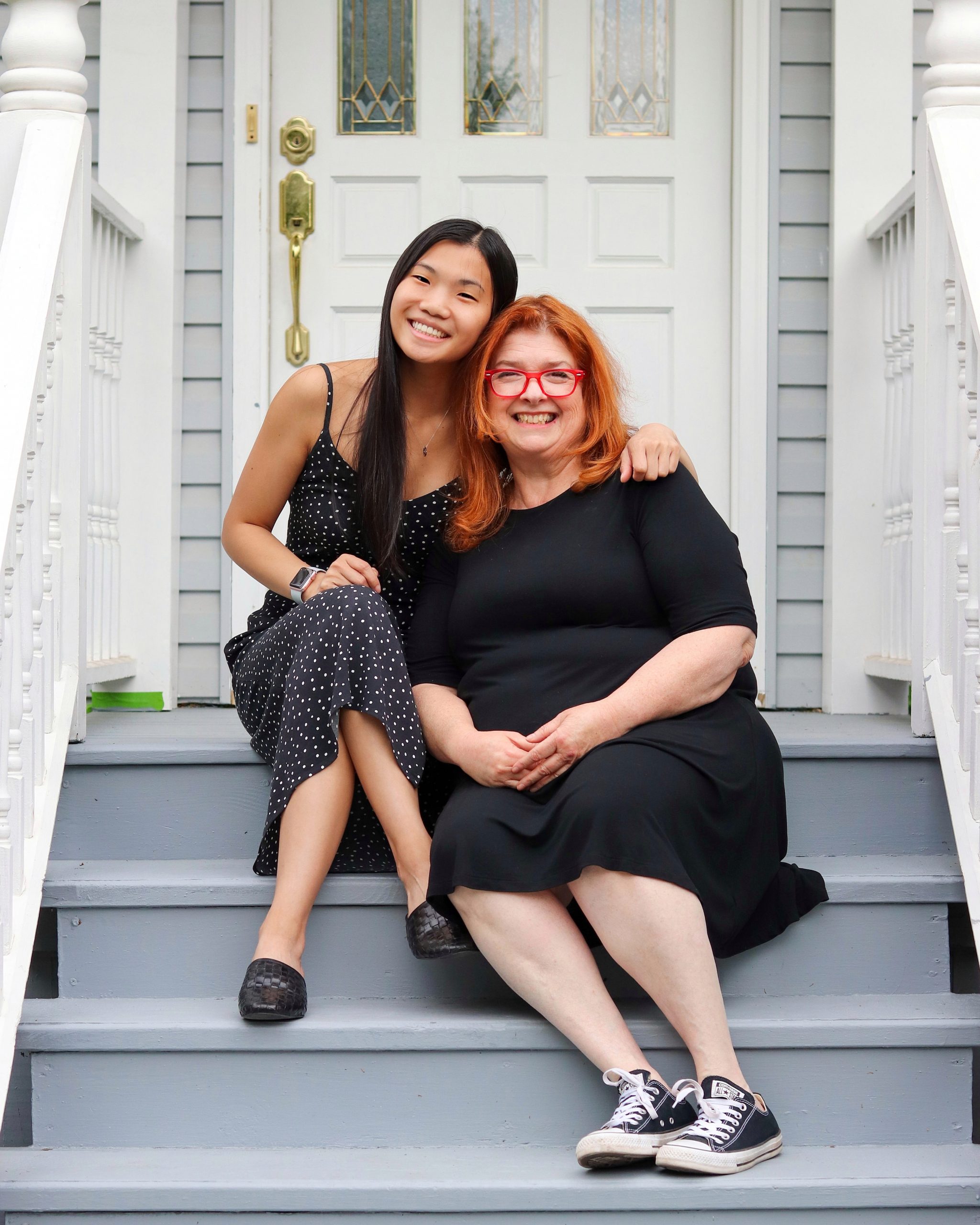 Image: A young adult woman sitting on the front steps with her mom