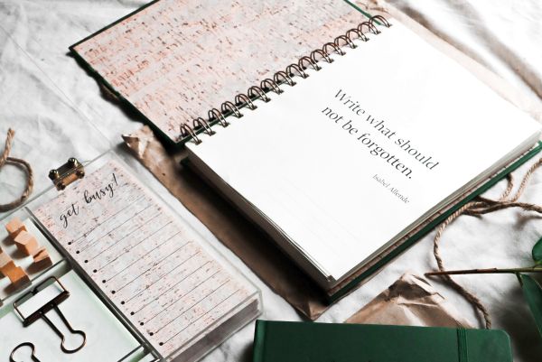 Image: An open journal with a quote reading, "Write what should not be forgotten."