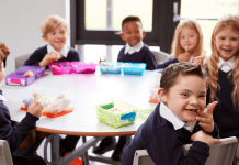 Image Description: several diverse children sit together at a school table for lunch
