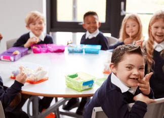 Image Description: several diverse children sit together at a school table for lunch
