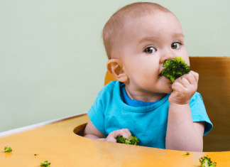 A baby girl trying some solid food (Overcoming My Solid Feeding Fears: A Journey of an Anxious Mom Andrea Wood & Cindy Herde Contributors Miami Mom Collective)