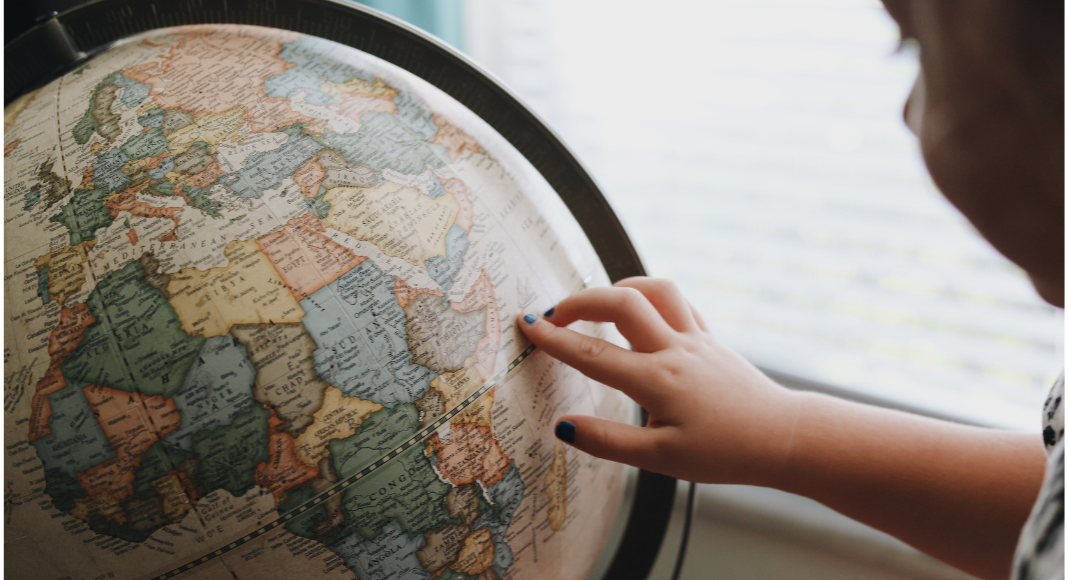 A little girl looking at a globe (Tooth Fairy Traditions From Around The World | Dr. Bob Pediatric Dentist Lynda Lantz Contributor Miami Mom Collective)