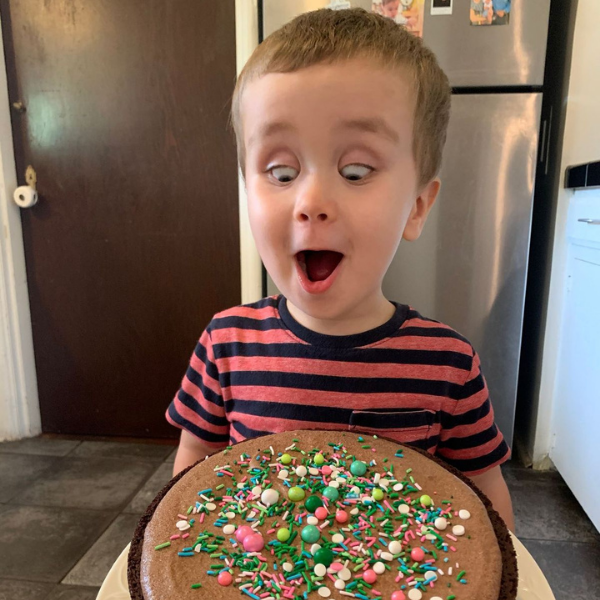 "How I Went Gluten-Free" Image: a young boy in a striped shirt looks down excitedly at a chocolate cake with sprinkles. (How I Went Gluten-Free Brittany Aquart Contributor Miami Mom Collective)