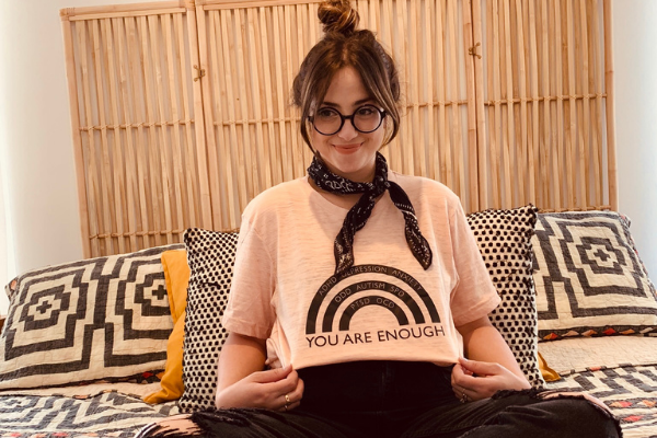 Jacqueline posing with a rainbow t-shirt that reads, "You are enough."