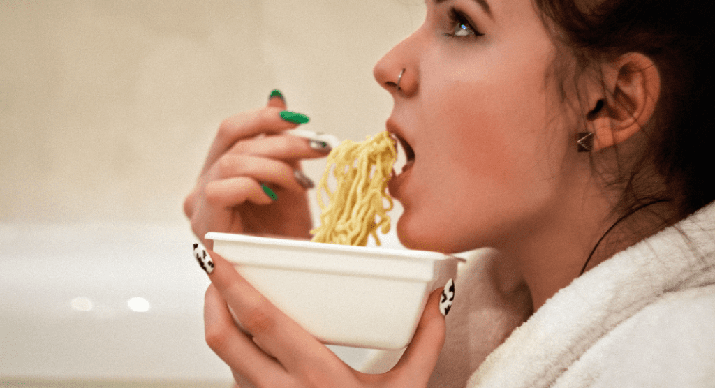 A woman eating a bowl of ramen noodles