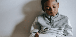 Stuck Inside? Try These Gross Motor Games! Image: A boy sitting with a book in his lap (Stuck Inside? Try These Gross Motor Games! Brittany Aquart Contributor Miami Mom Collective)