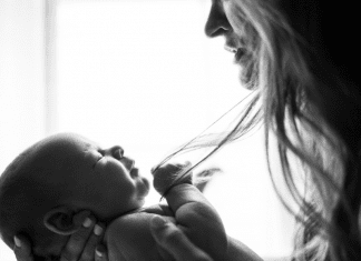 A mother holding her infant (To Parent in a Broken World Kristin Parke Contributor Miami Mom Collective)