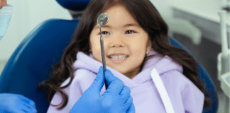 A young girl at the dentist's office (Going Back to the Dentist? 3 Things to Consider | Dr. Bob Pediatric Dentist Lynda Lantz Contributor Miami Mom Collective)