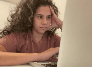 Image: Zoe sitting in front of her computer (5 Tips to Manage Stress through Motherhood Zoe Costa Contributor Miami Mom Collective)
