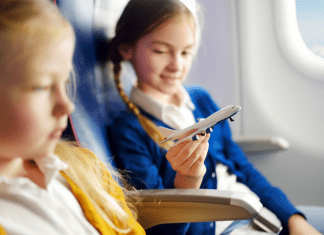 Image: Two girls sitting together on an airplane (Holiday Travel: The Ultimate Prep List for Smooth Family Travel Vanessa Santamaria Contributor Miami Mom Collective)