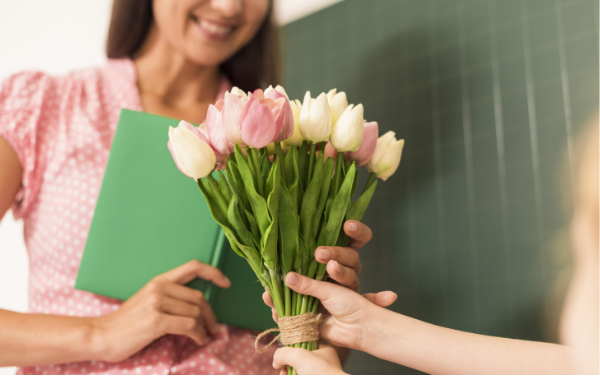 Image: A student handing a teacher a bouquet of flowers
