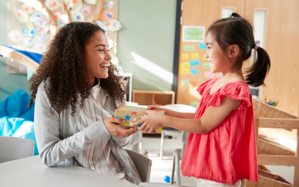 Image: A little girl giving a gift to her teacher