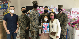 Image: Adita and her daughter with several US Marines standing in front of Toys for Tots collection boxes (Toys for Tots: Making a Difference for America's Children Adita Lang Contributor Miami Mom Collective)