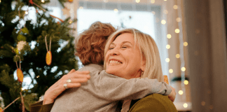Image: A grandmother hugging her grandson at Christmas (Holiday Travel and Gatherings: Protecting Your Family From COVID & Flu Lynda Lantz Editor Miami Mom Collective)