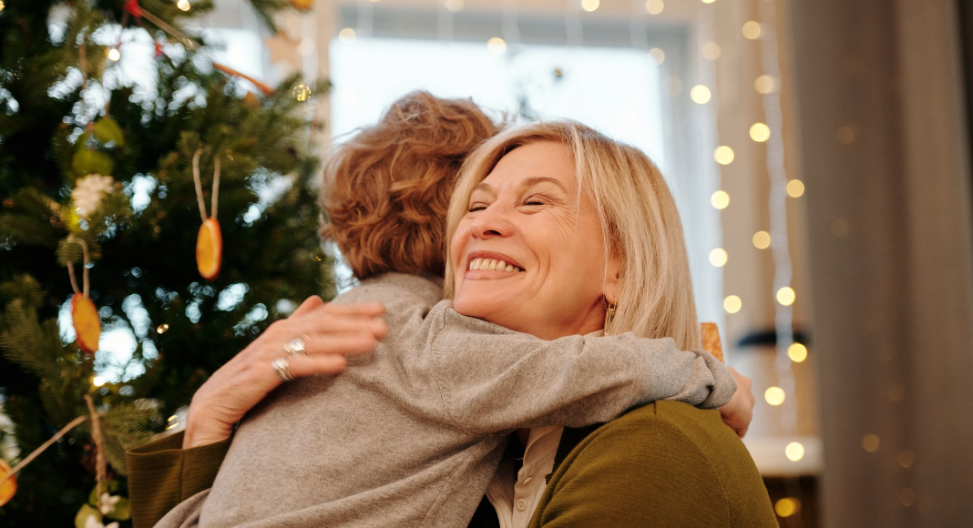 Image: A grandmother hugging her grandson at Christmas (Holiday Travel and Gatherings: Protecting Your Family From COVID & Flu Lynda Lantz Editor Miami Mom Collective)