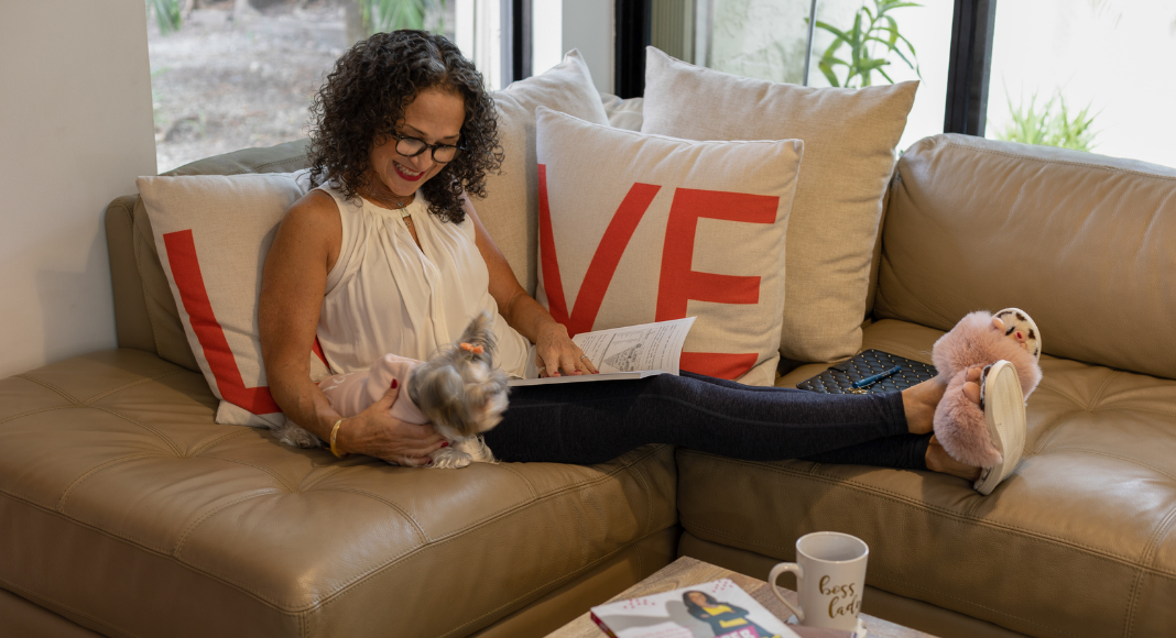 Image: Adita relaxing on her couch with a book (Mama, It's Time to Prioritize YOU! Adita Lang Contributor Miami Mom Collective)