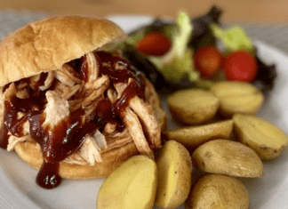 A BBQ pulled chicken sandwich, served with roasted potatoes and salad