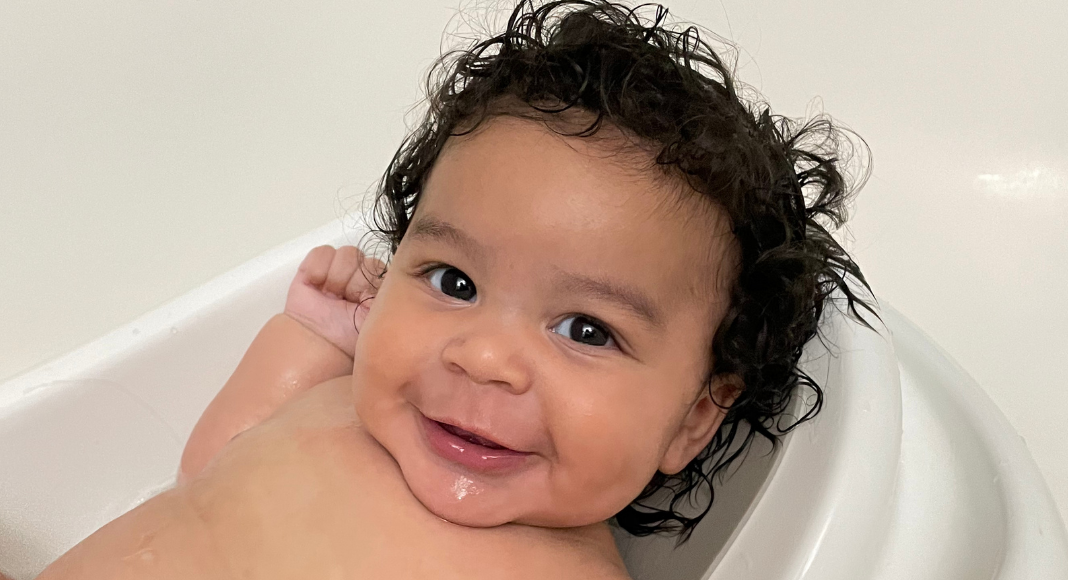 A baby relaxing and smiling at the camera