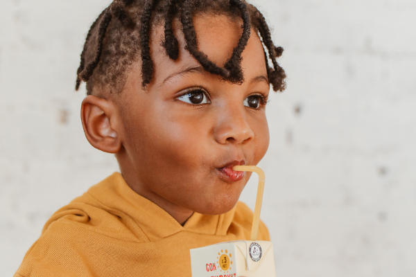 A little boy drinks from a juice box with a straw