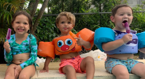 Three kids eating popsicles by the pool