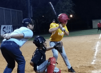 Little league baseball players standing behind home plate