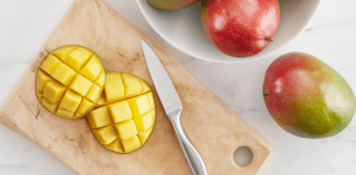 Mango Season: Fun and Delicious Recipes to Make With Mangos Image: A sliced mango on a wooden cutting board