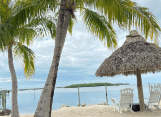 Two beach chairs under a chiki umbrella on a beach in Islamorada