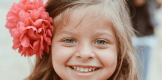 A little girl with a flower in her hair, showing off her smile
