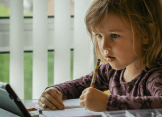 A little girl works on a lesson on her device