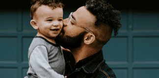 A father holding giving his toddler-aged son a kiss on the cheek