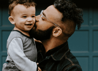 A father holding giving his toddler-aged son a kiss on the cheek