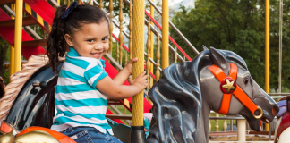 5 Healthy Hacks for Theme Park Trips A little girl riding on a carousel at a theme park
