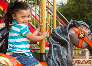 A little girl riding on a carousel at a theme park