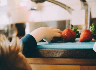 A toddler reaches to grab some fresh fruit