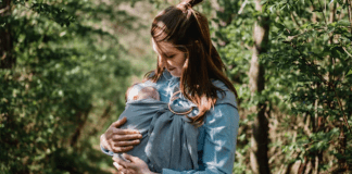 Post-Partum Crisis: Is This a Thing? A postpartum mom wearing her newborn baby in a sling