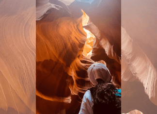 A child looks up at the sunlight shining through a canyon