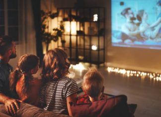 A family sitting on the couch, watching a movie together