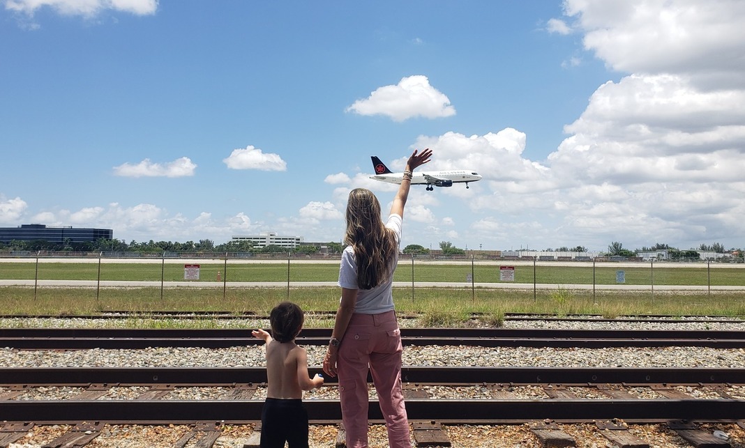 Five Different Activities to Try This Summer with Kids - Sandra Jacquemin Image: Sandra and her son watch and wave as an airplane lands at MIA