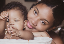 Image: A Black mother smiles while her infant plays