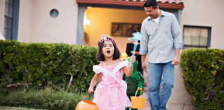 Image: A little girl trick-or-treating with her dad