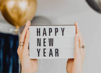 Image: Hands hold up a letter board that reads "Happy New Year"
