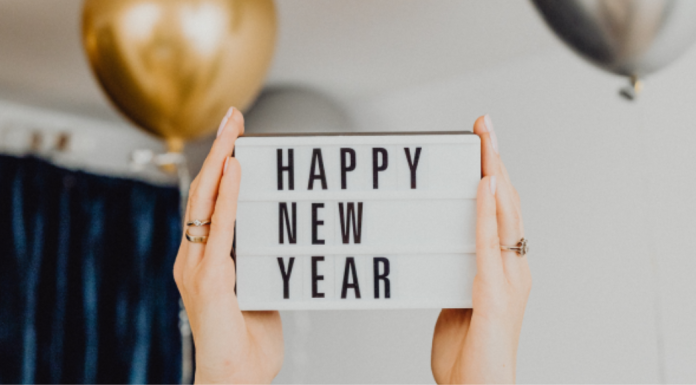Image: Hands hold up a letter board that reads "Happy New Year"